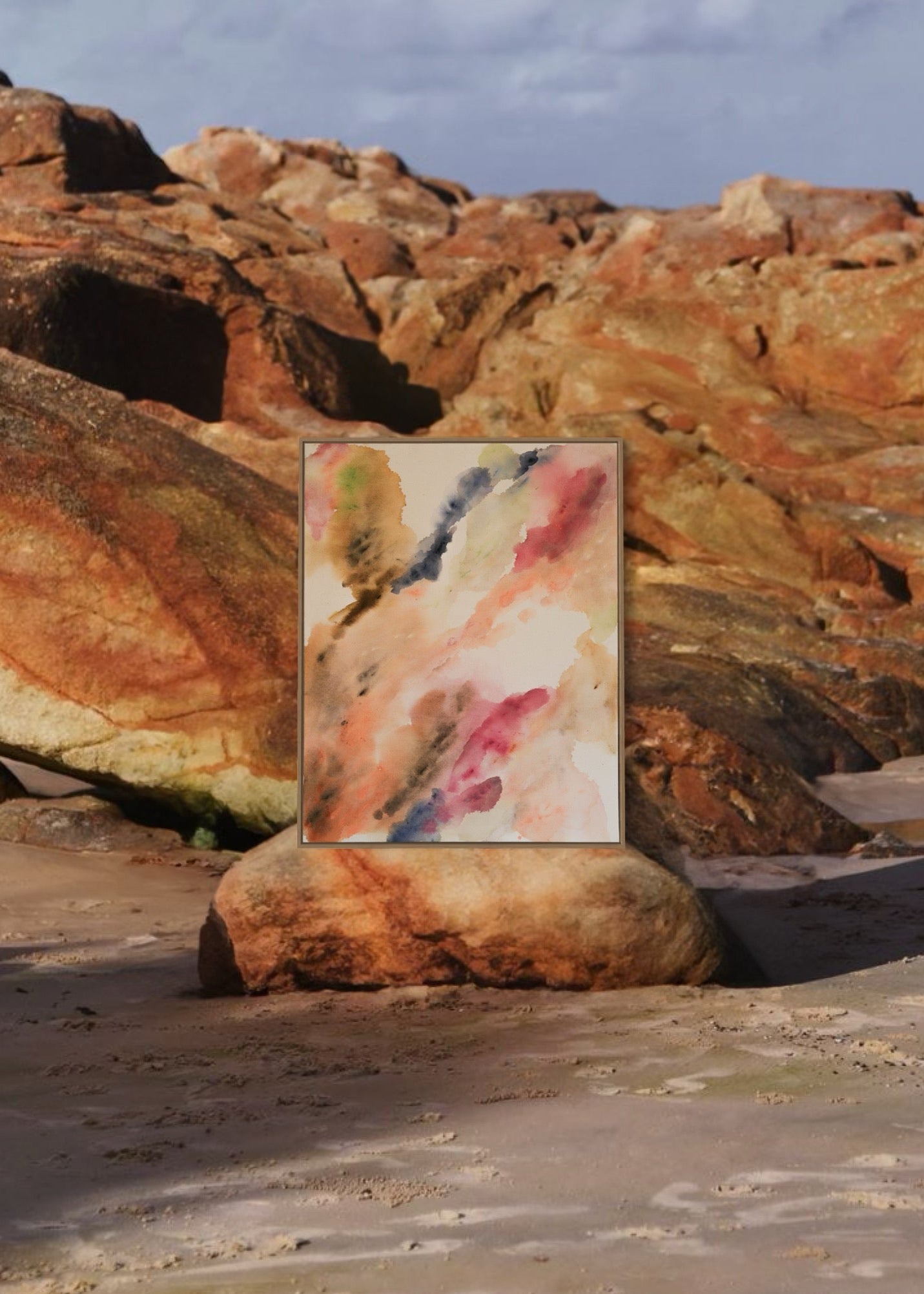 Abstract watercolor in earthy tones such as beige, rose, orange, and brown, with touches of blue and green. The colors flow transparently into one another on a white background, framed in a slim, wooden frame.