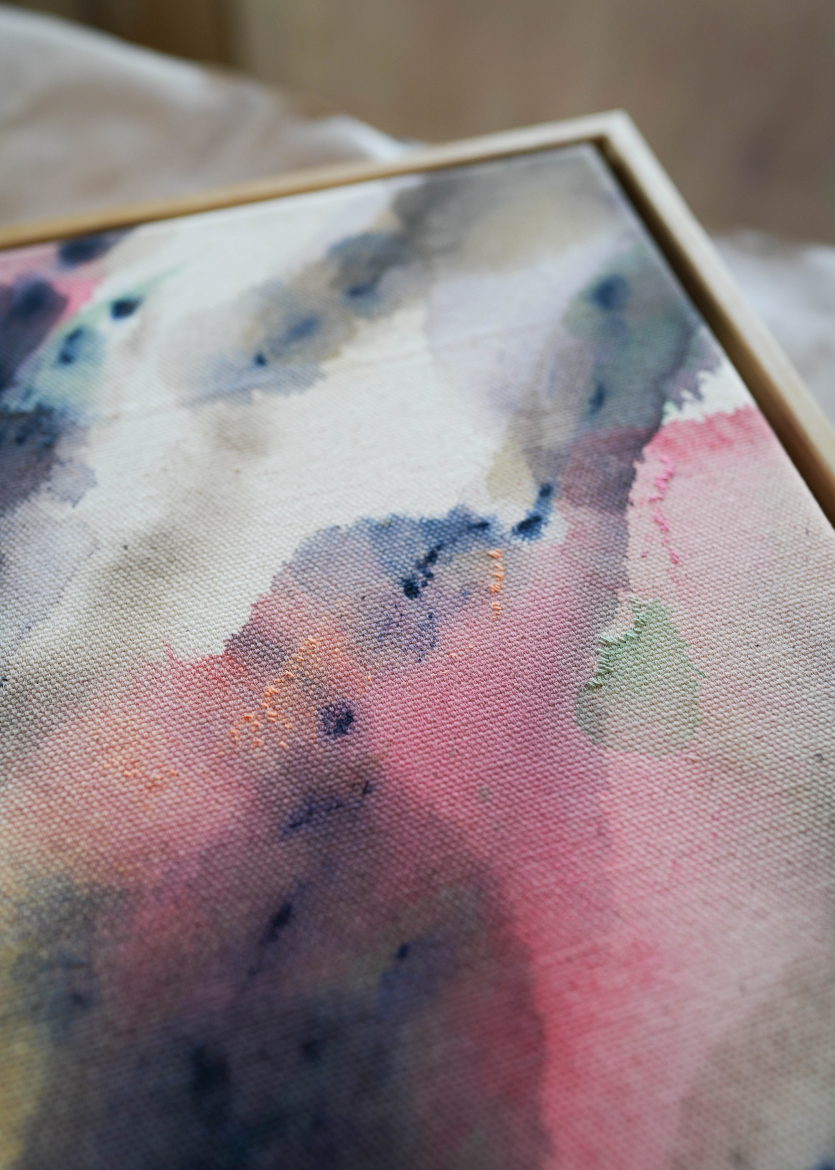 The abstract acrylic painting shows blended swirls of pink, blue, and earthy colors on textured cotton canvas. It creates a calm and peaceful mood.
