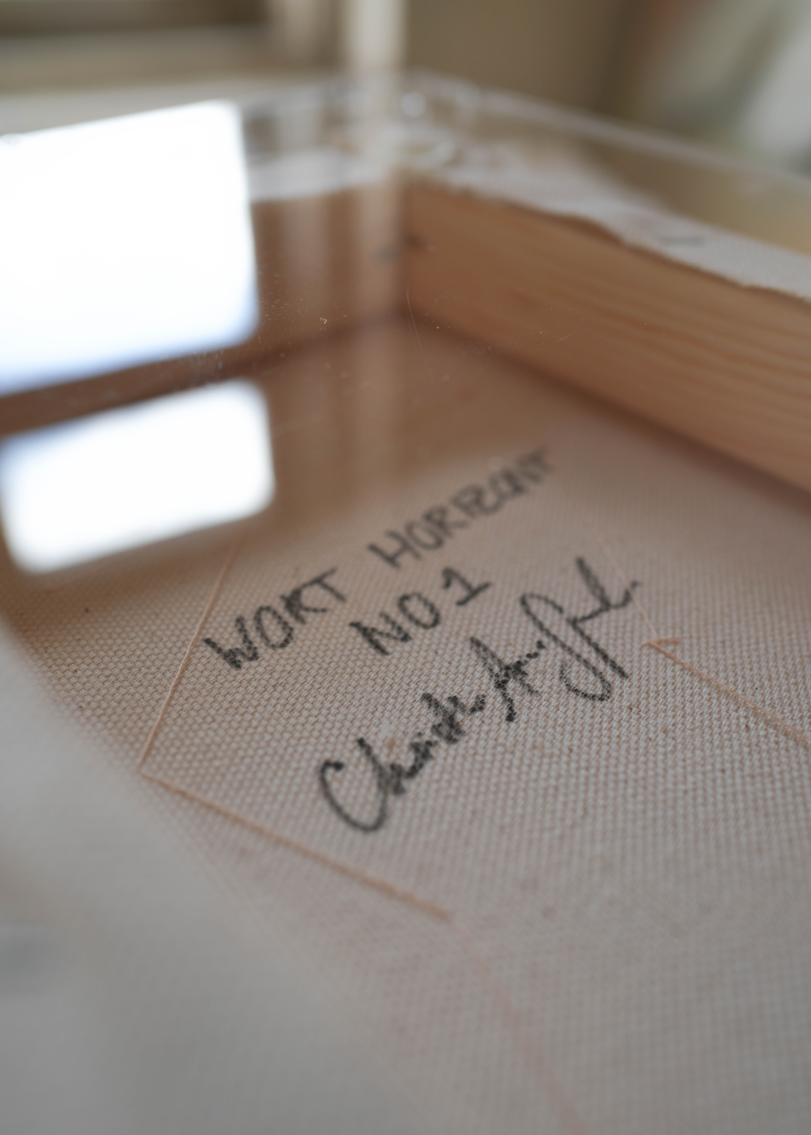 Backside of an abstract painting featuring purple, dark purple, and beige brushstrokes on canvas. With a stitched poem that reads, "everything I need already exists in me." Framed in clear acrylic.