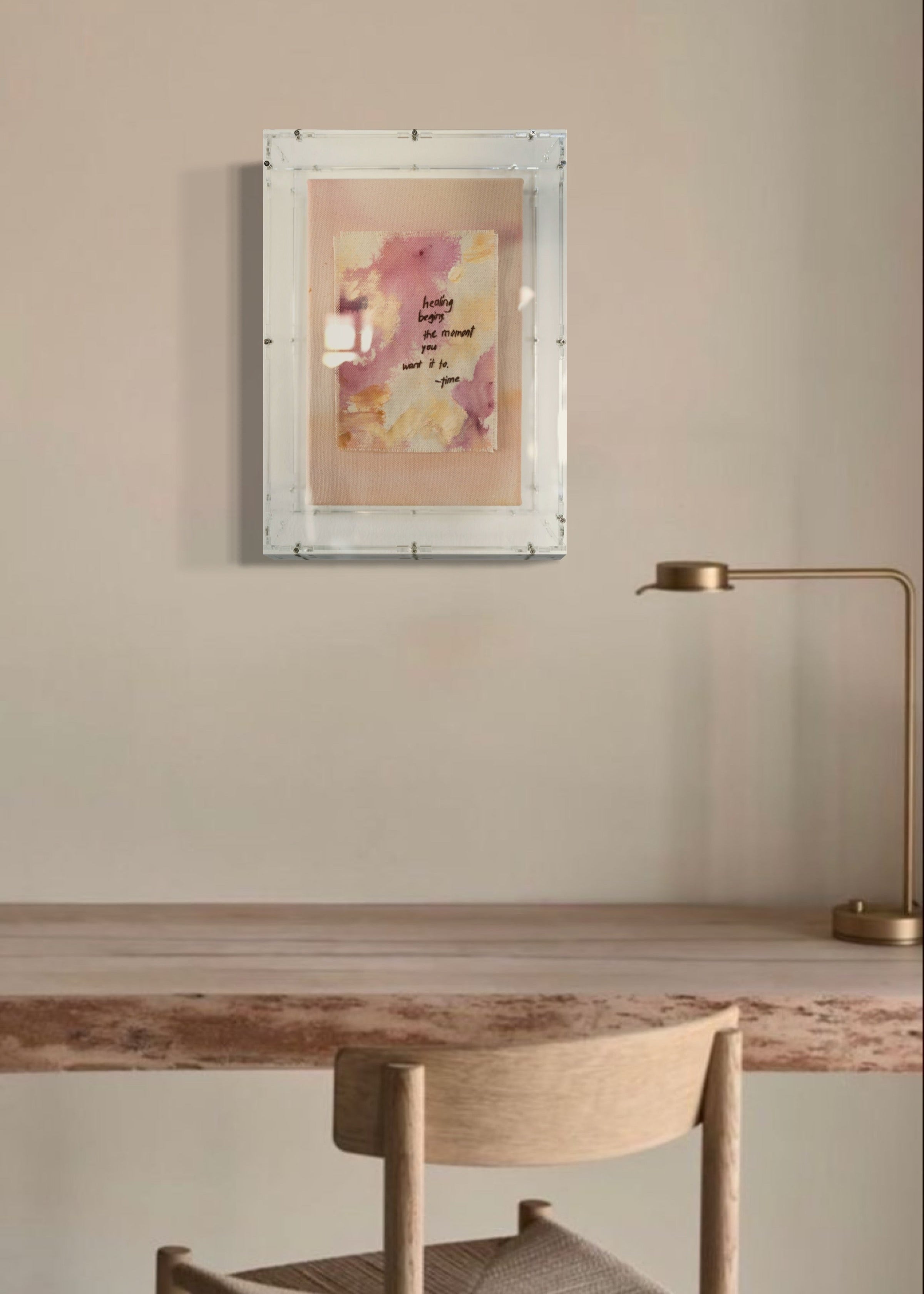 The abstract painting features a soft pink, beige, and orange watercolor background. It has a hand-stitched poem that says, "Healing begins the moment you want it to." This artwork radiates hope and is beautifully framed in clear acrylic.