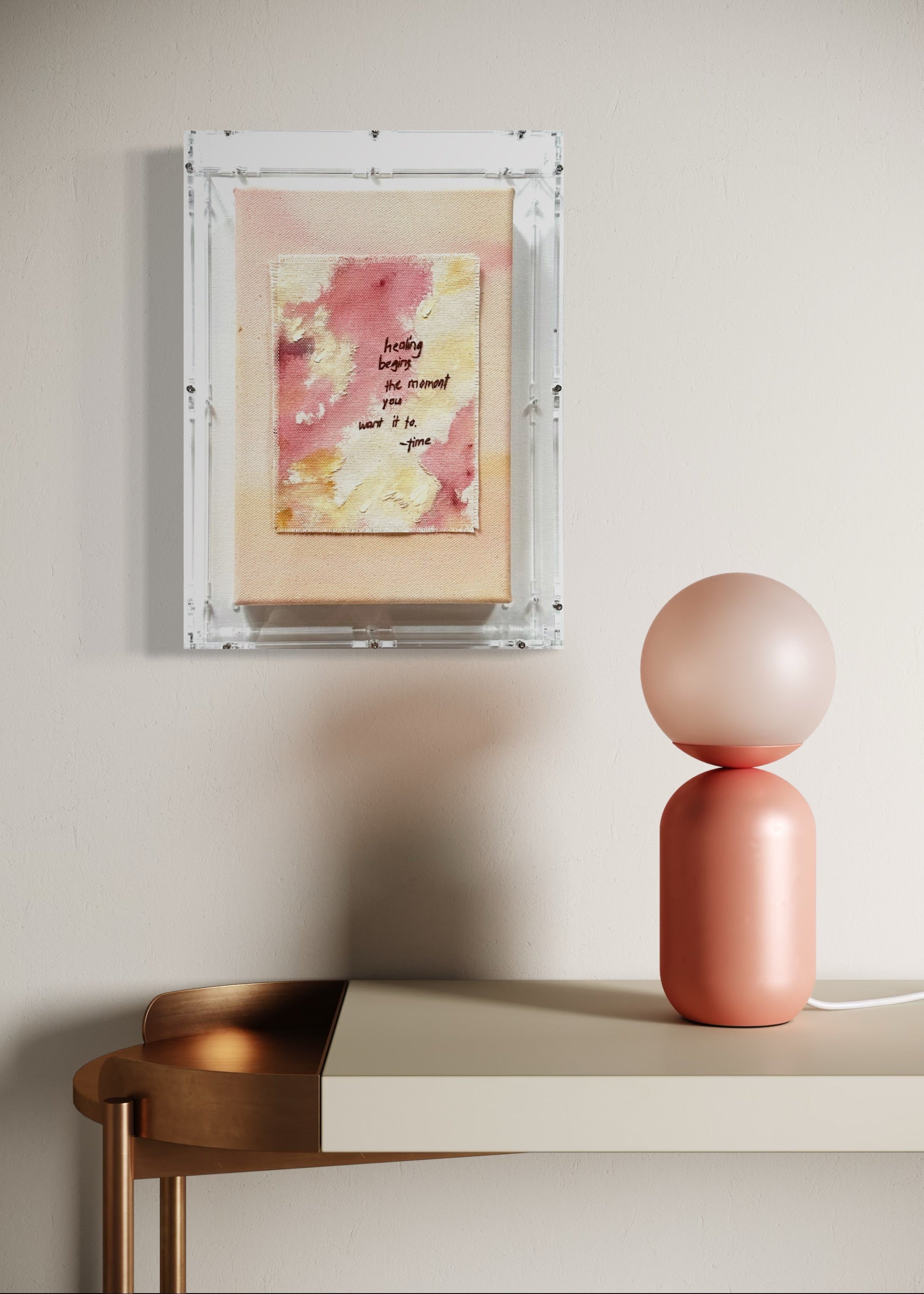 The abstract painting features a soft pink, beige, and orange watercolor background. It has a hand-stitched poem that says, "Healing begins the moment you want it to." This artwork radiates hope and is beautifully framed in clear acrylic.