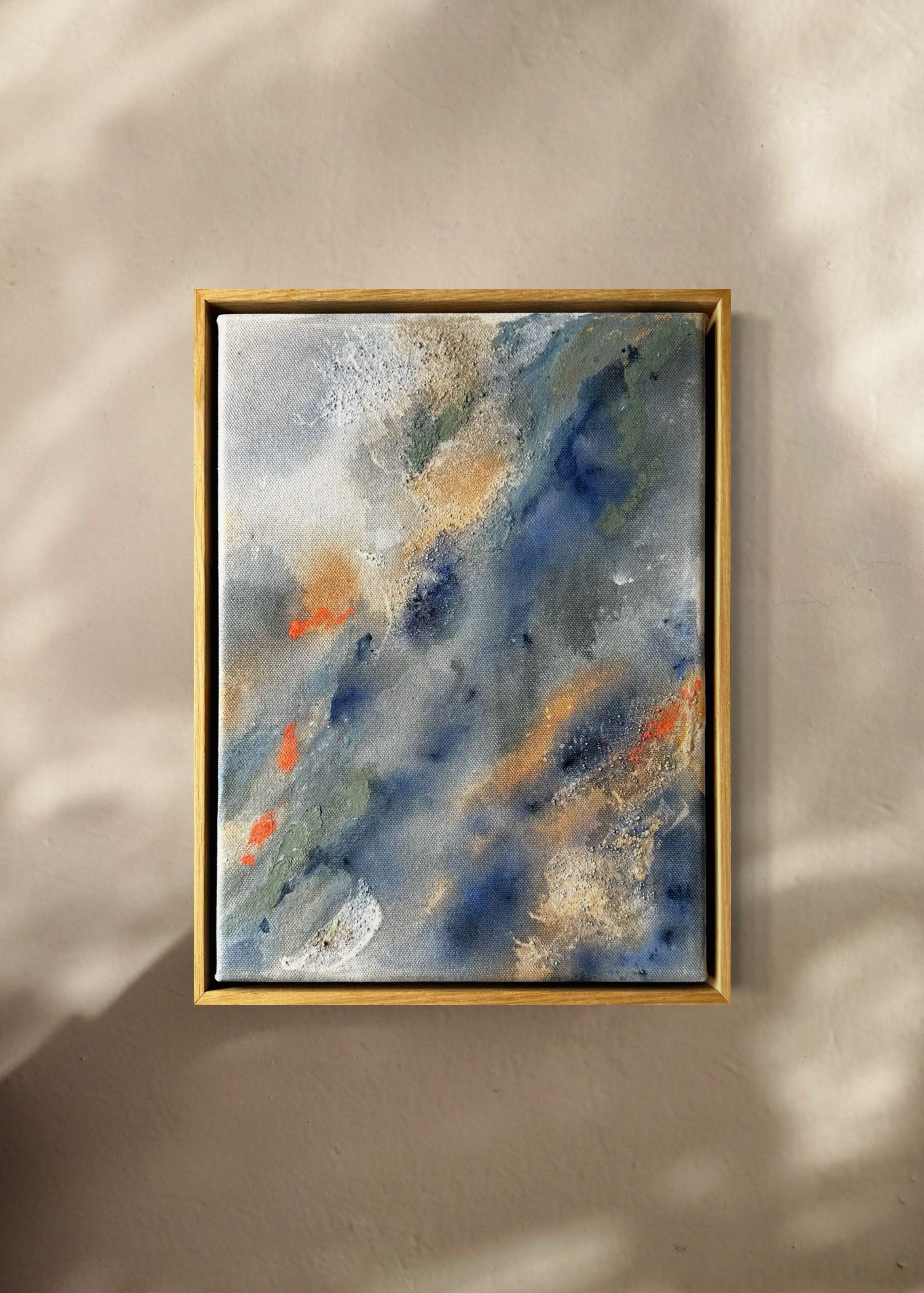 Abstract painting with swirling patterns in shades of blue, gray, green and orange, framed in oak wood.