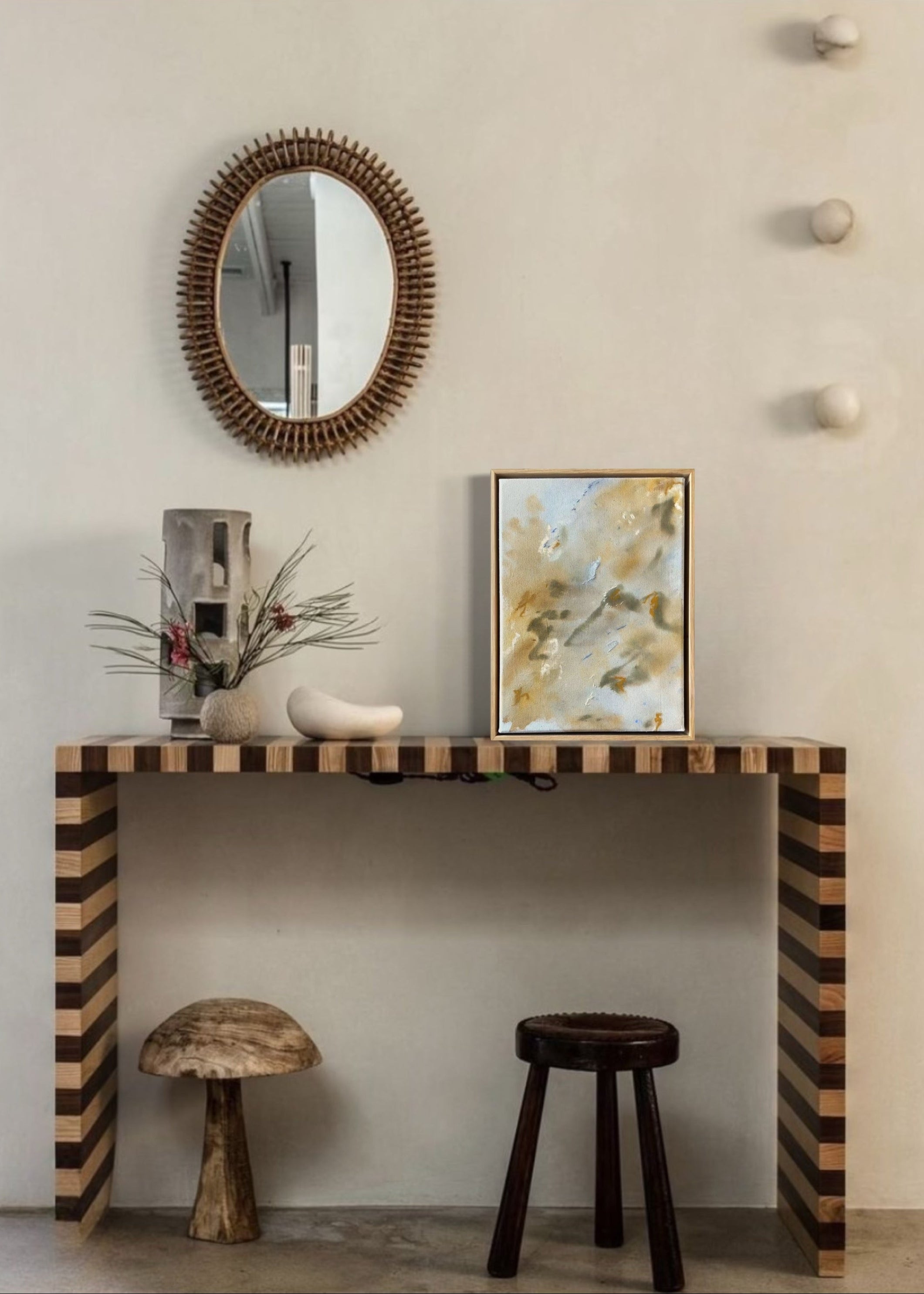 Abstract painting featuring soft, blended colors in beige, brown, and hints of blue. The artwork has a textured, stitched surface and is framed in a light oak wood frame.