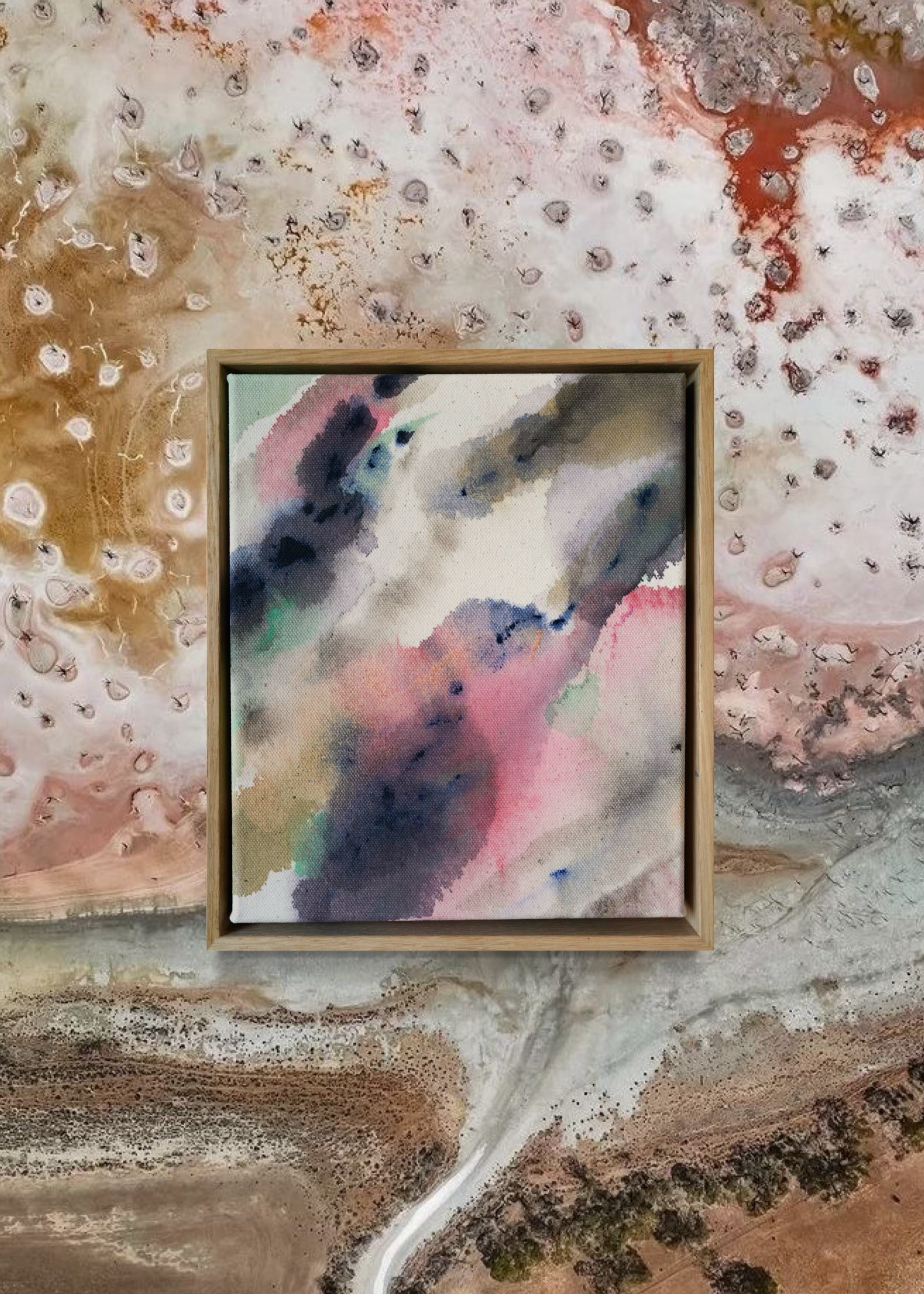 Abstract acrylic painting in a wooden frame displays blended swirls of pink, blue, and earthy tones on textured cotton canvas, evoking a serene mood.
