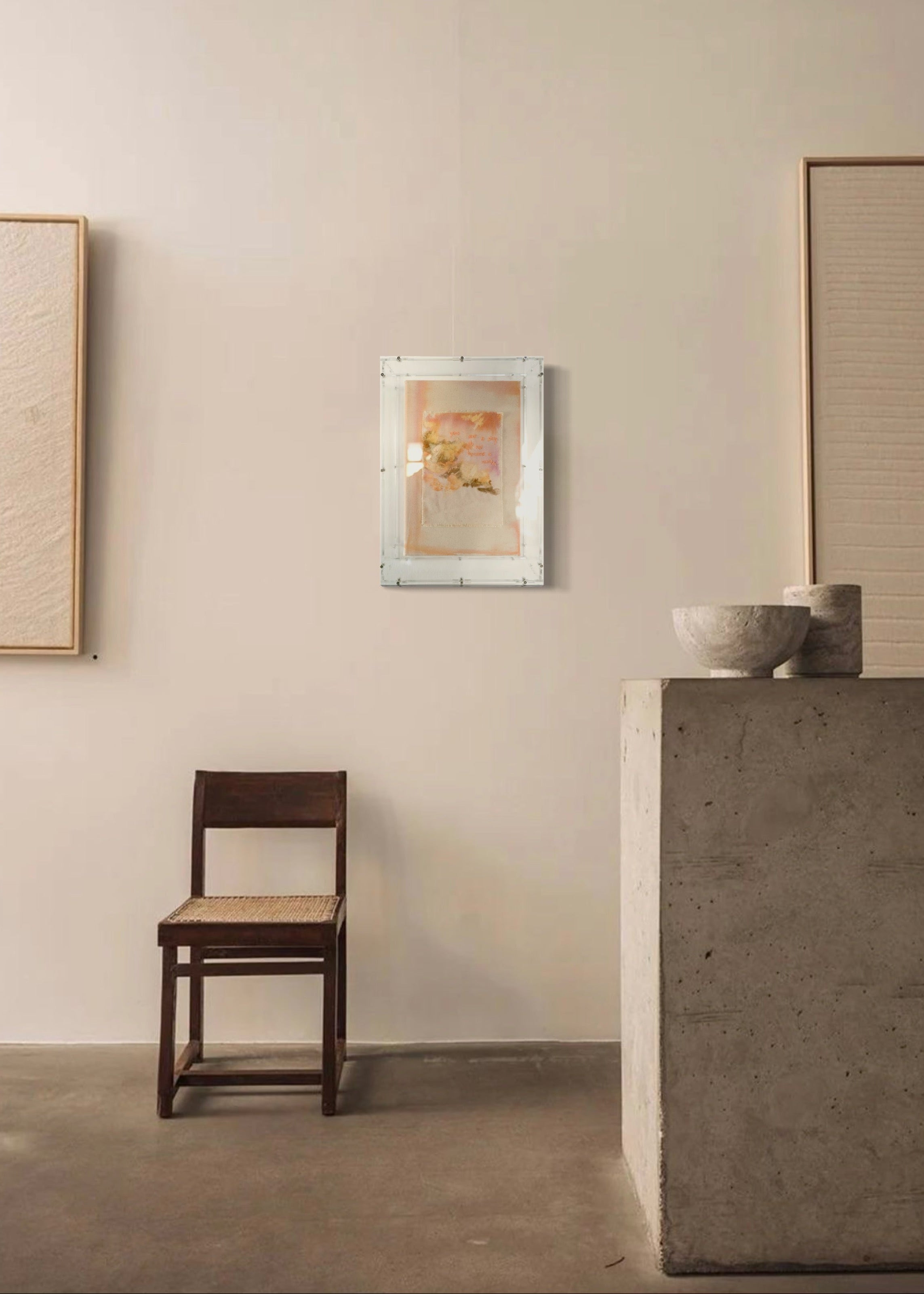 This textured abstract artwork showcases soft pastel shades of pink and orange. It features gentle brushstrokes and embroidered text that reads, "You are a story; do not become a word." The piece is elegantly framed in clear acrylic.