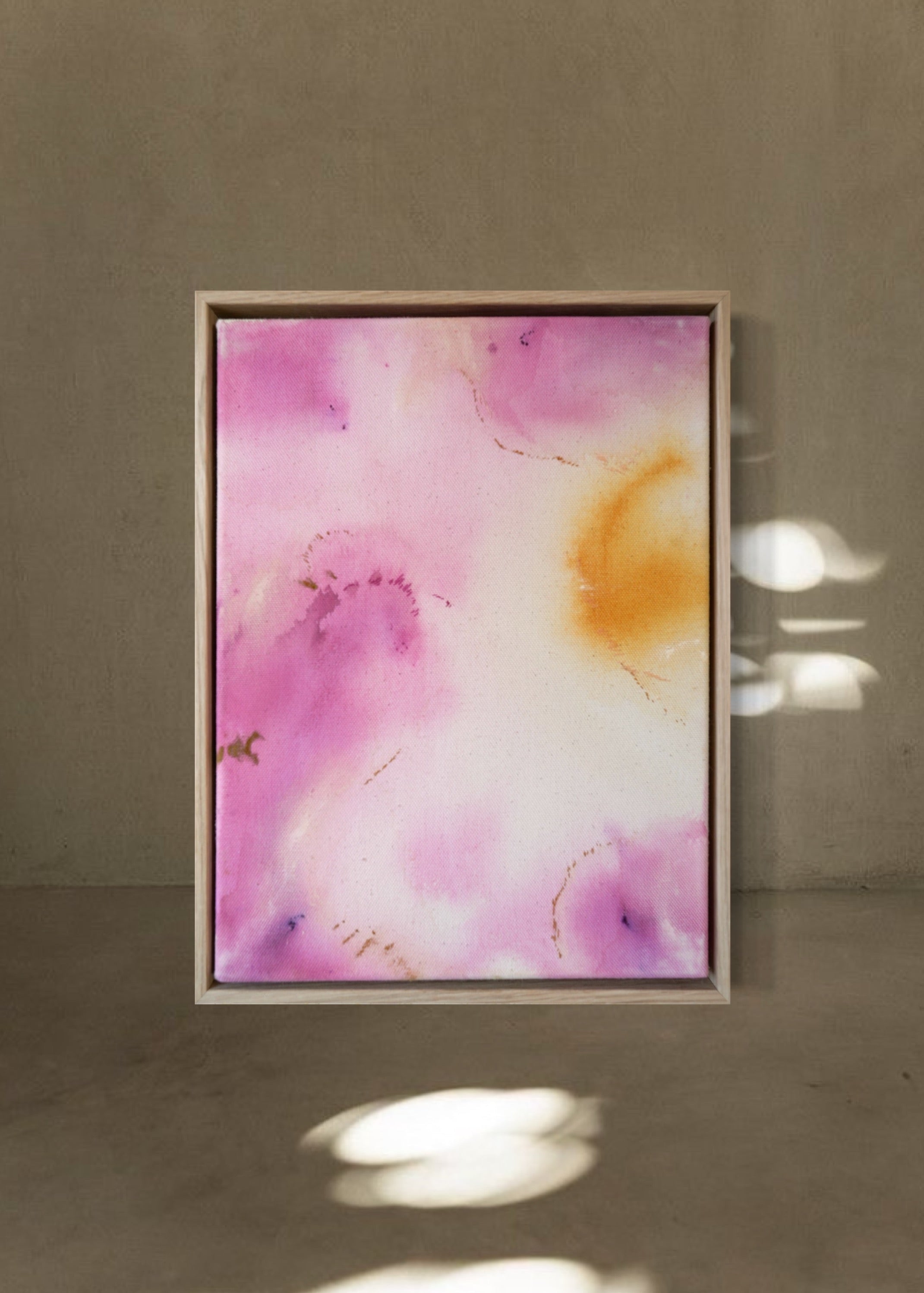 Abstract painting featuring soft pink, purple, and orange hues blending together with embroidery details of gold and dark purple on a canvas, framed in light wood.