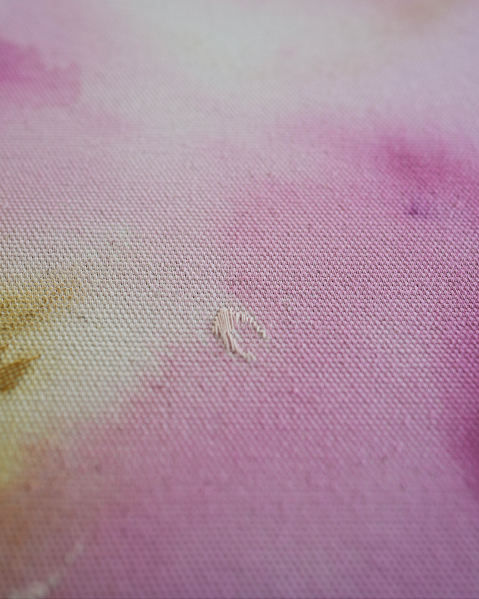 Abstract painting with soft pink, purple, and orange colors blending together. It has gold and dark purple embroidery details on a canvas. The painting is framed in light wood.