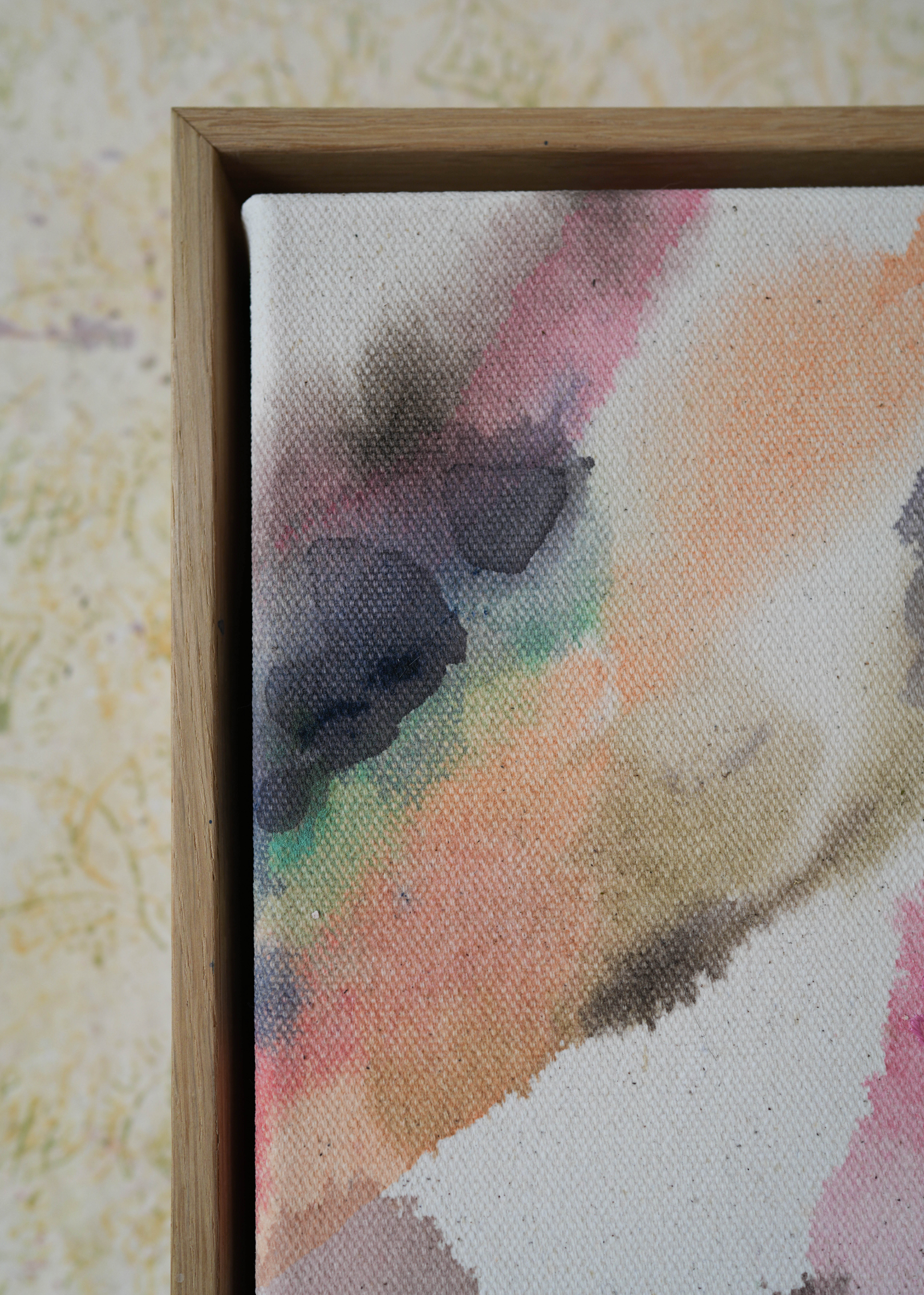 Abstract acrylic, fluid painting with soft pink, peach, green, and dark grey splashes, framed by light wood, conveying an impressionistic and soothing tone.