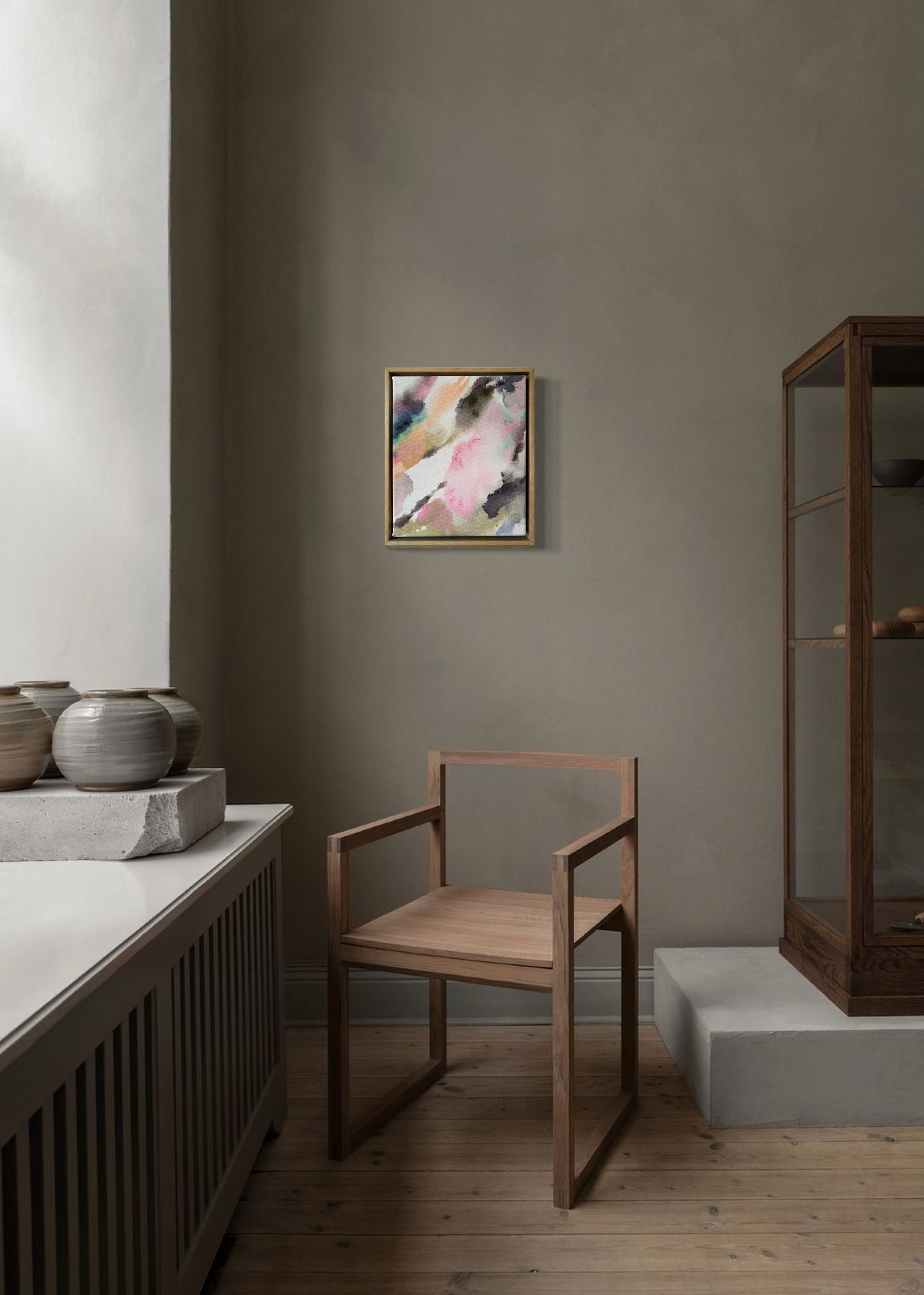 Abstract acrylic, fluid painting with soft pink, peach, green, and dark grey splashes, framed by light wood, conveying an impressionistic and soothing tone.