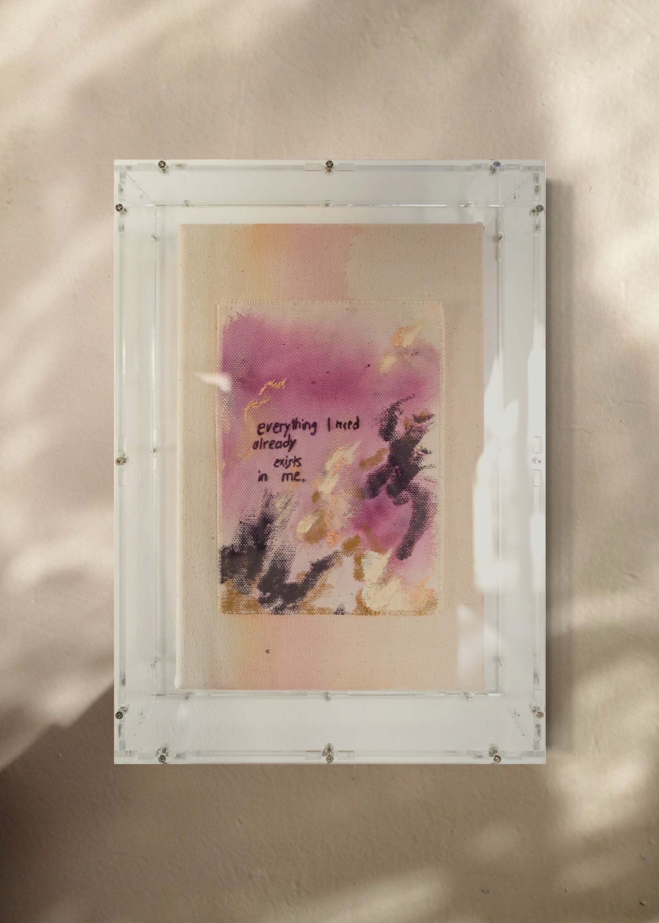 Abstract painting featuring purple, dark purple, and beige brushstrokes on canvas. With a stitched poem that reads, "everything I need already exists in me." Framed in clear acrylic.