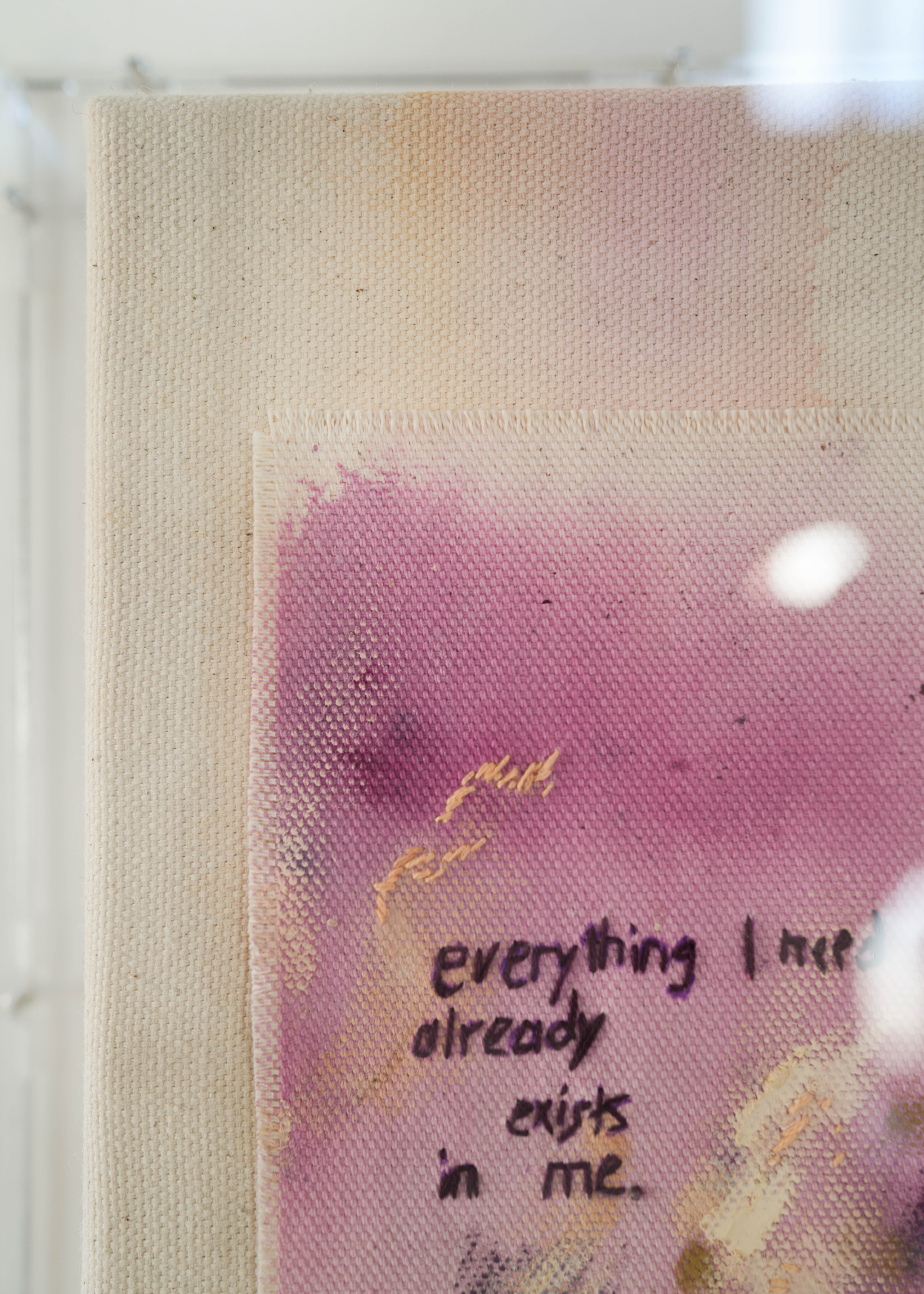 Abstract painting featuring purple, dark purple, and beige brushstrokes on canvas. With a stitched poem that reads, "everything I need already exists in me." Framed in clear acrylic.