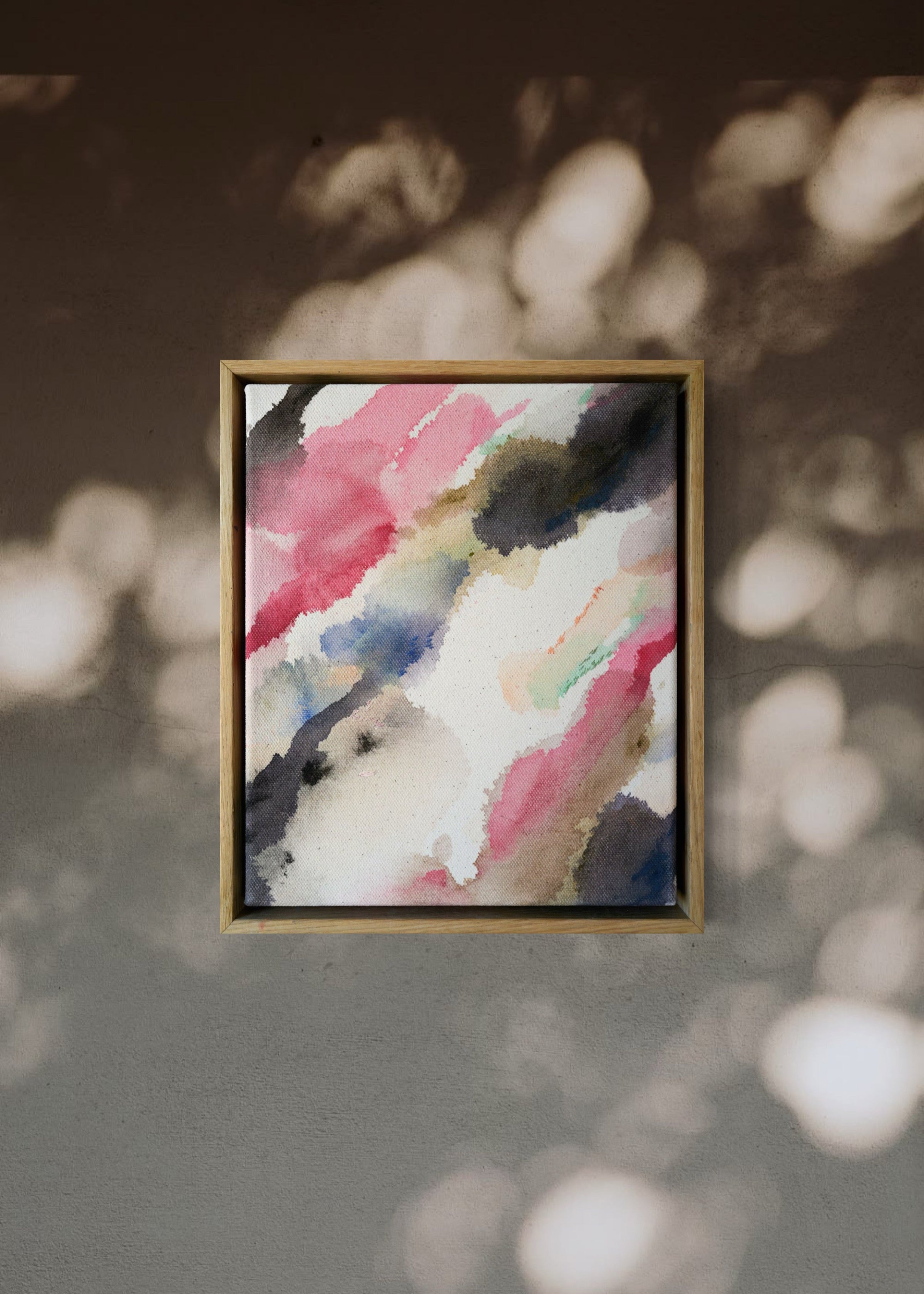 Abstract acrylic watercolor painting in a wooden frame. Soft pink, grey, and brown hues blend on a raw canvas, creating a calm, fluid effect.
