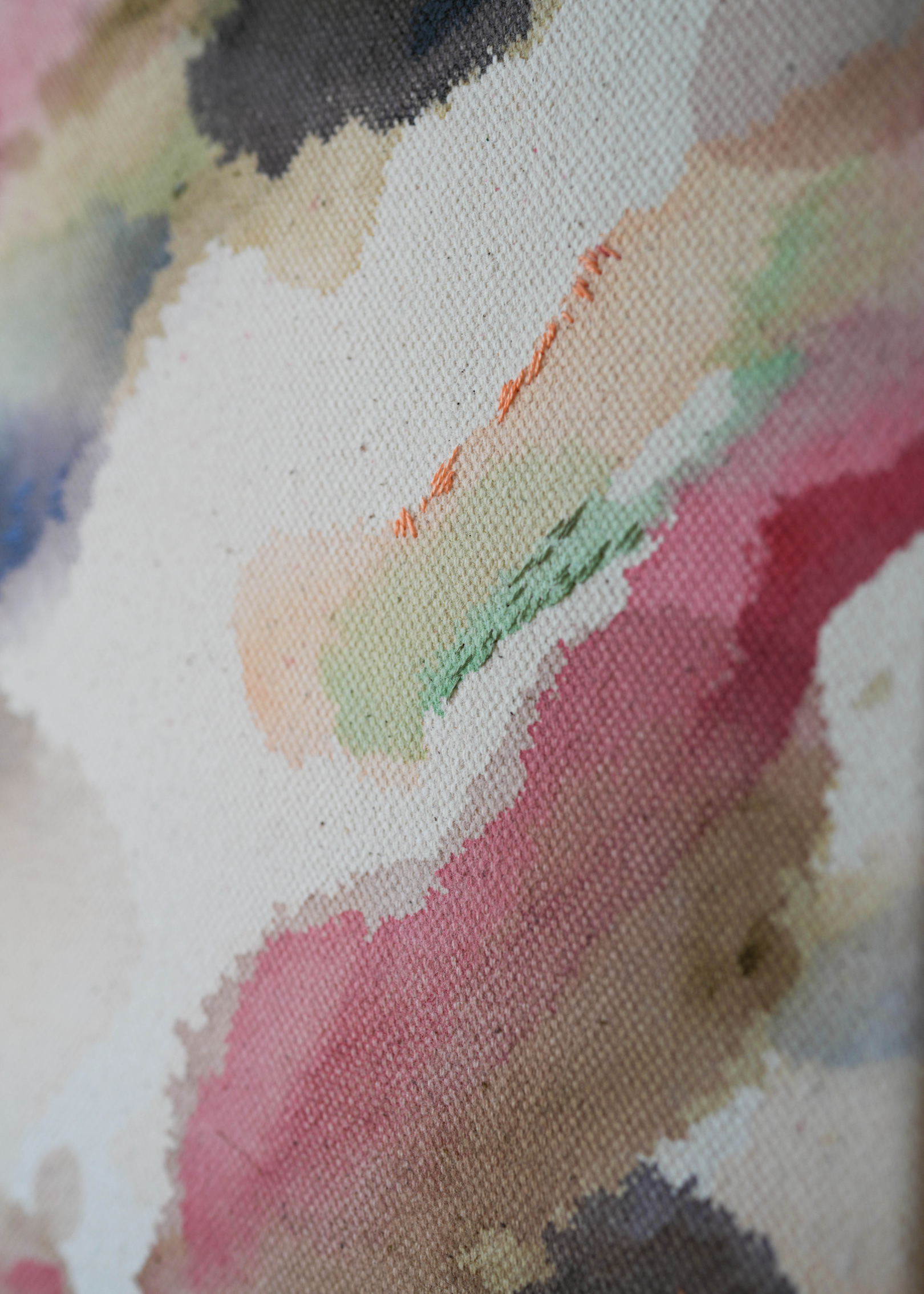 Abstract acrylic watercolor painting in a wooden frame. Soft pink, grey, and brown hues blend on a raw canvas, creating a calm, fluid effect.