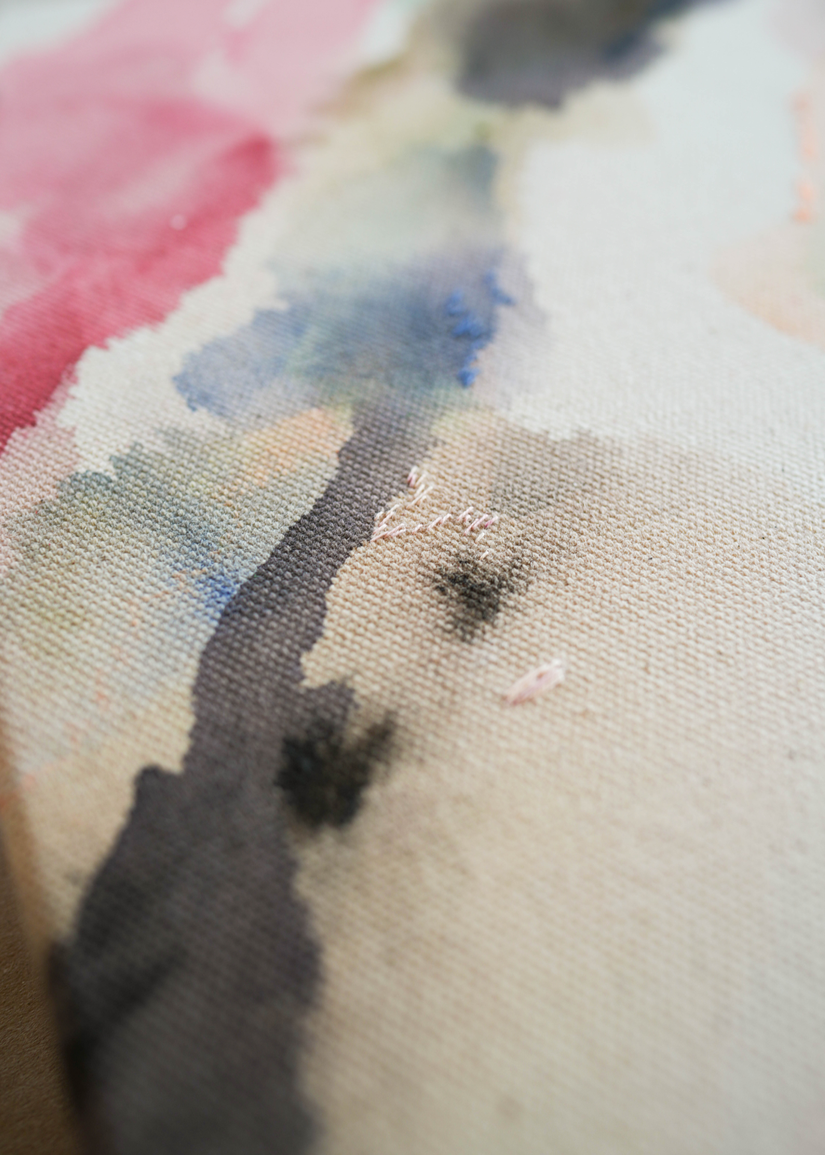 Abstract acrylic watercolor painting in a wooden frame. Soft pink, grey, and brown hues blend on a raw canvas, creating a calm, fluid effect.