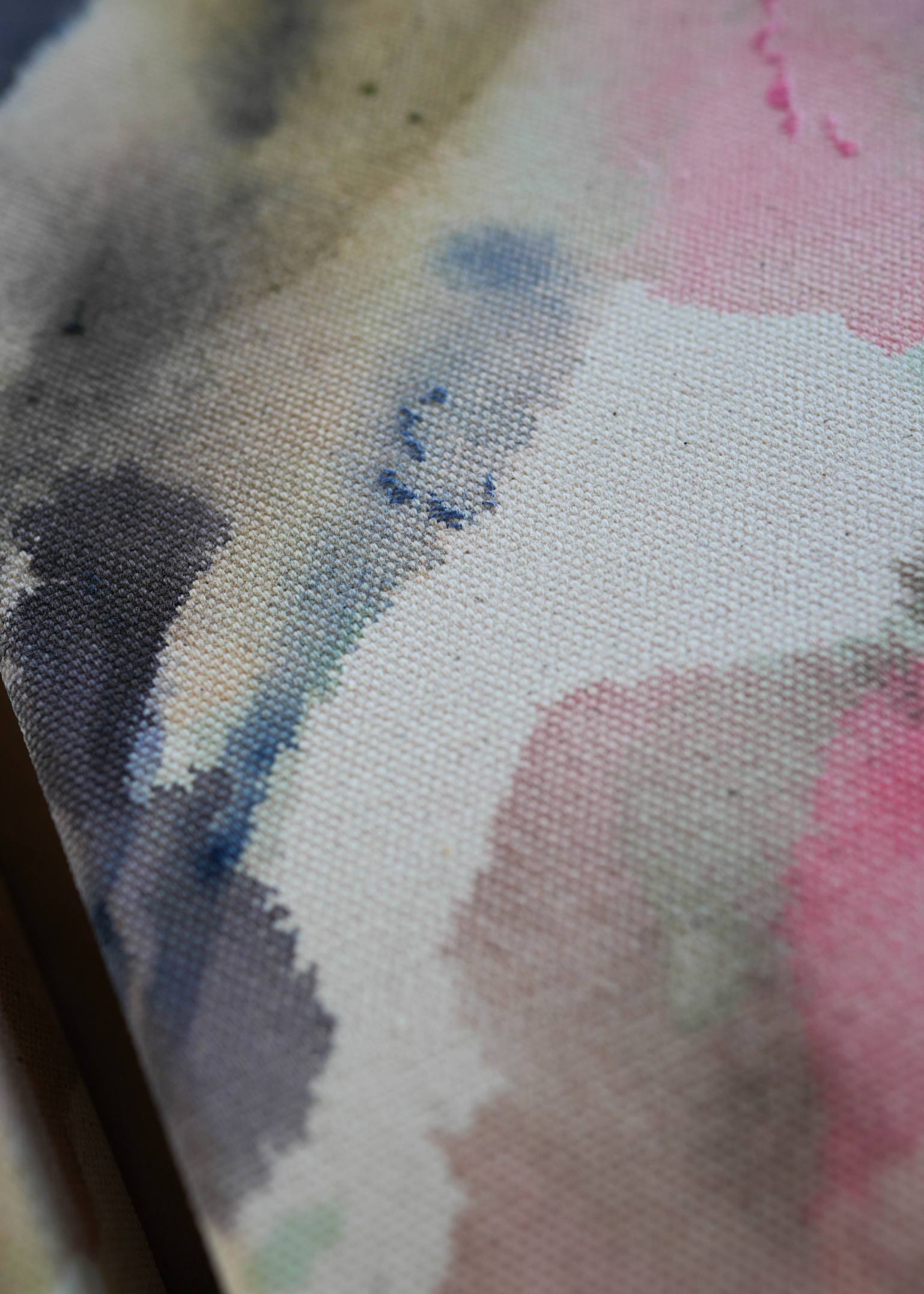 Abstract acrylic painting with pink, blue, and gray hues on raw canvas. Bordered by a wooden frame. Conveys a natural, ethereal mood.