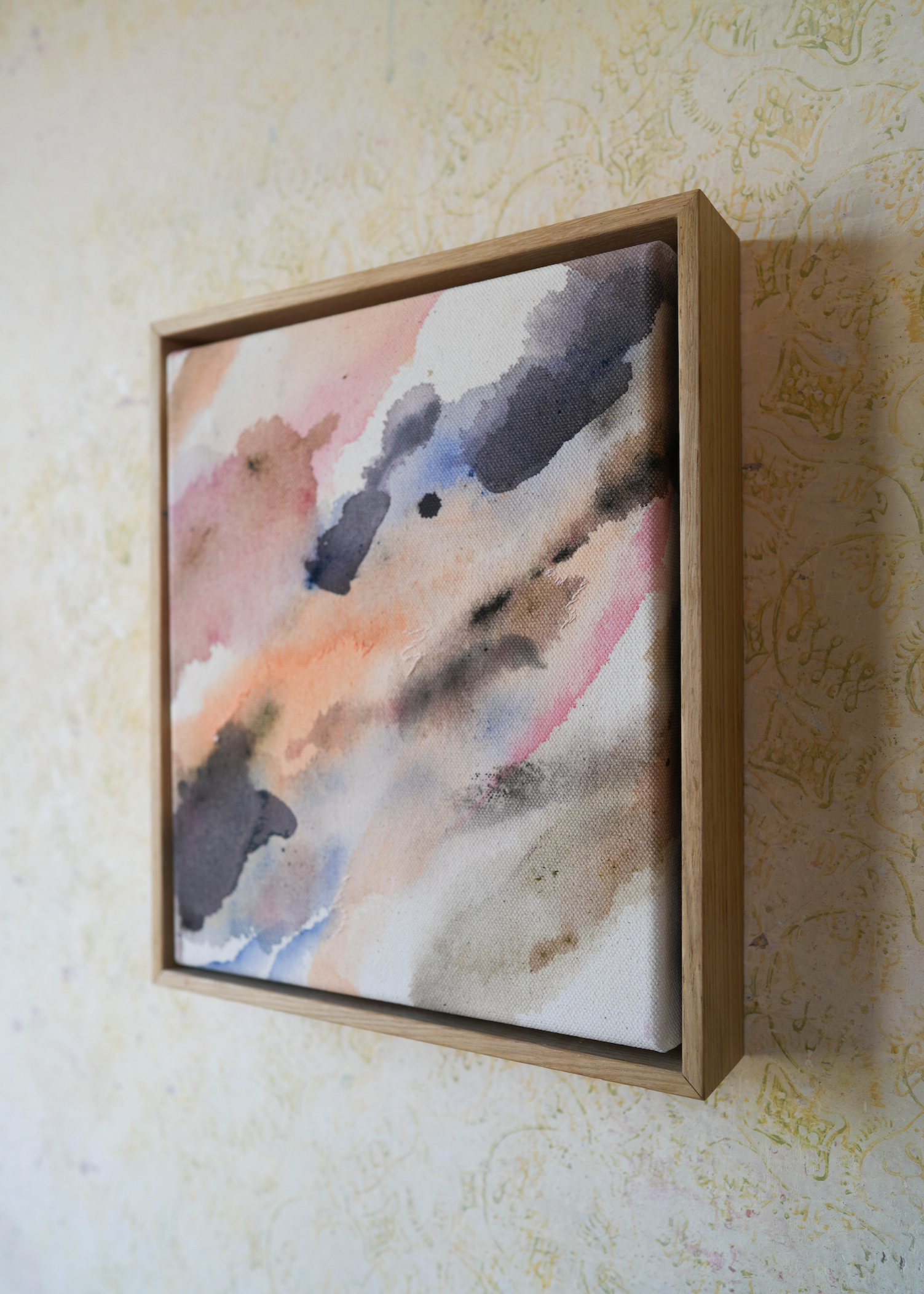 Abstract acrylic painting with soft, flowing shades of pink, peach, gray, and blue. Framed in light wood, the art conveys a calm, dreamy atmosphere.