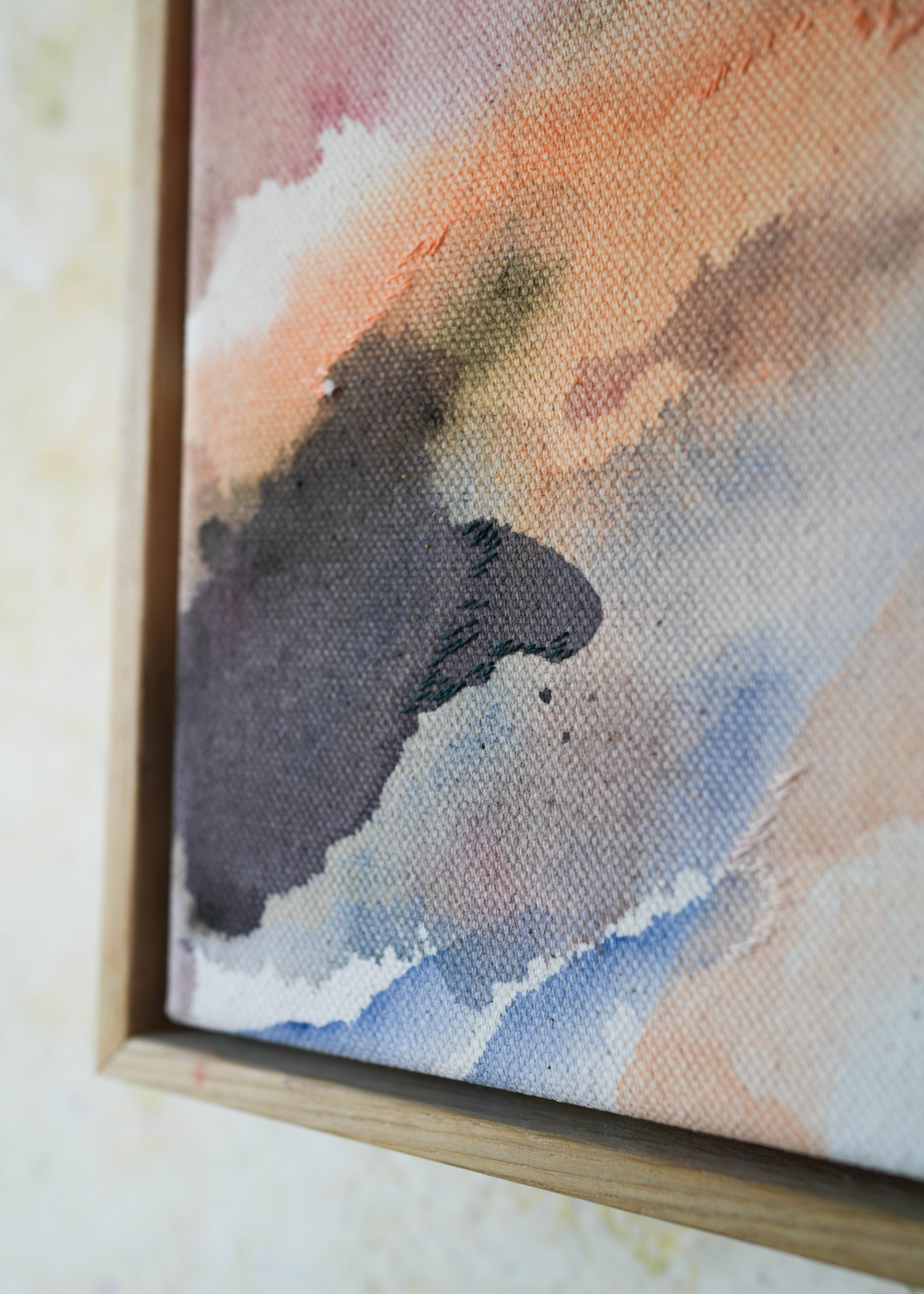 Abstract acrylic painting with soft, flowing shades of pink, peach, gray, and blue. Framed in light wood, the art conveys a calm, dreamy atmosphere.