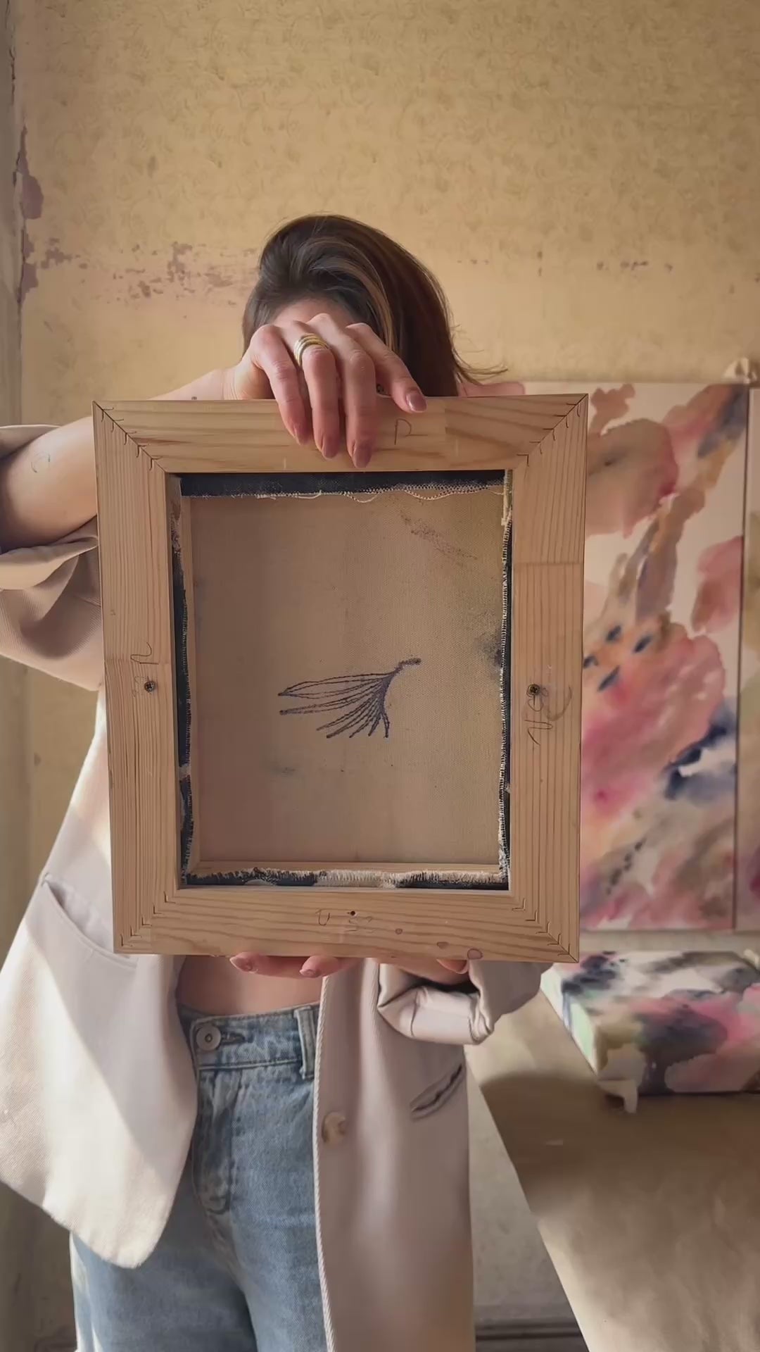 Video of an abstract painting with swirling blue and pink tones, framed in wood, evoking motion and emotion.