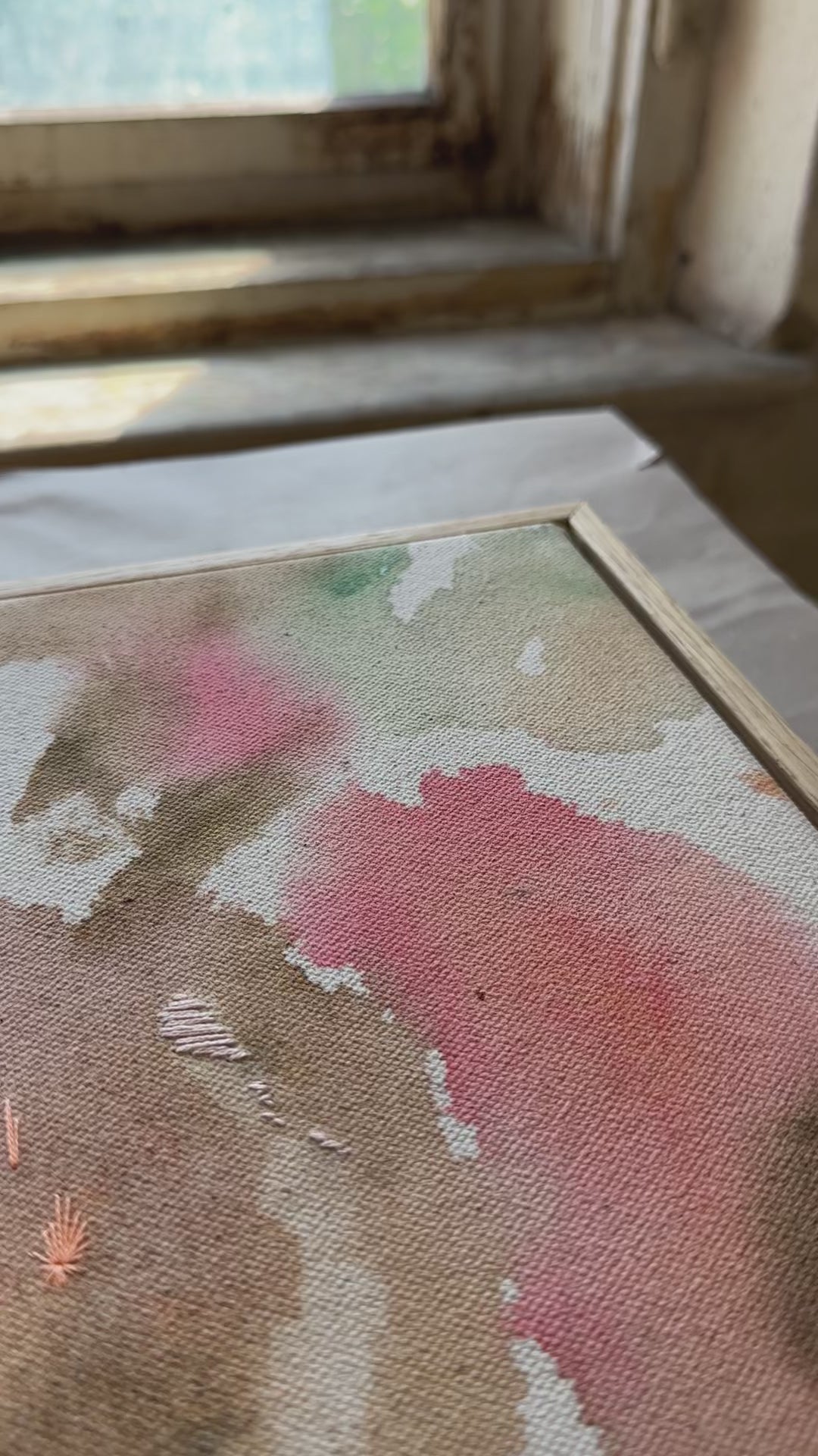Abstract painting featuring soft, flowing shapes in shades of pink, beige, orange, and green shades, with a textured appearance framed in oak wood.