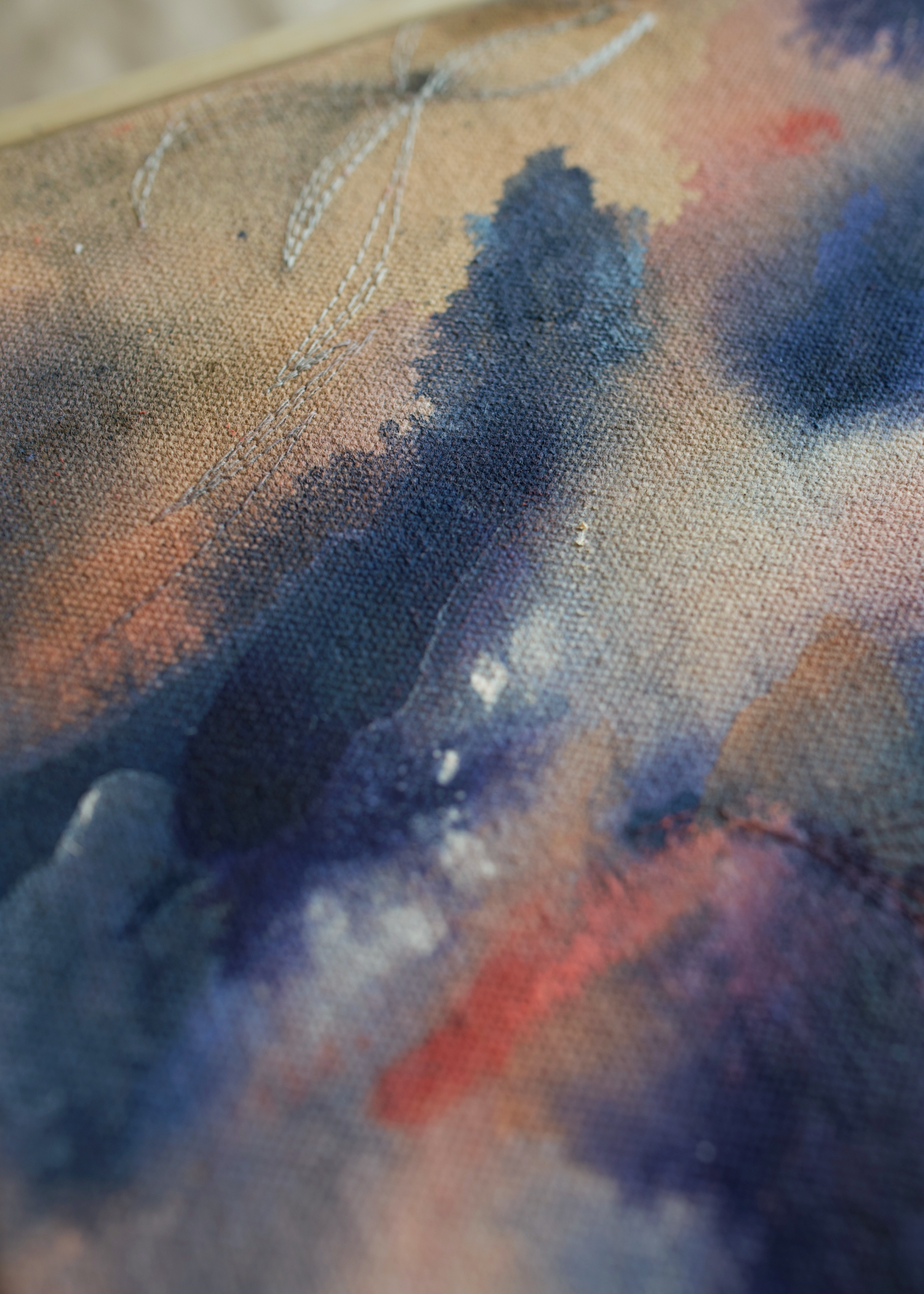 Detail shot of an abstract painting with swirling blue and pink tones, framed in wood, evoking motion and emotion.