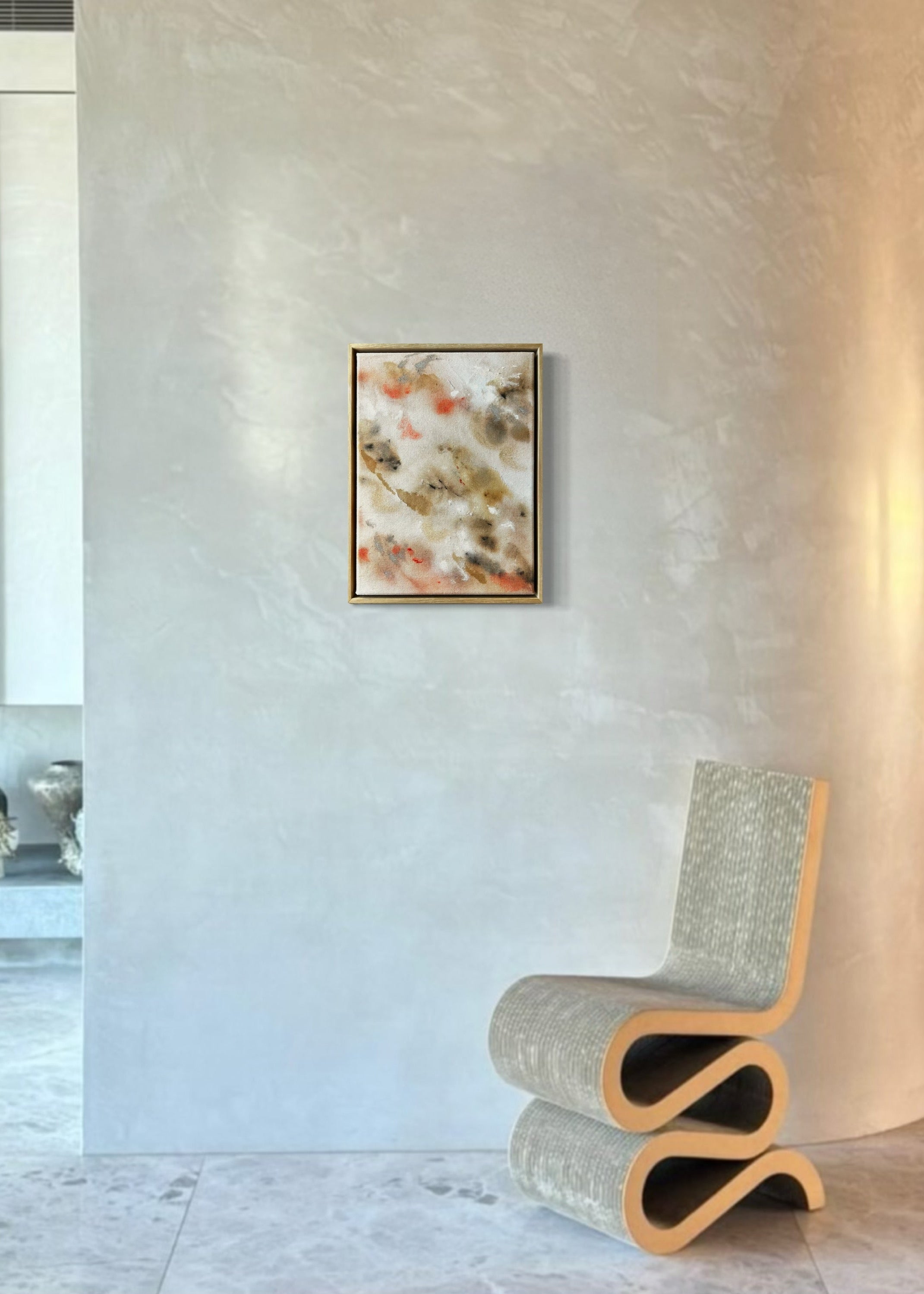 Abstract painting featuring soft, blended shapes in beige, brown, and hints of orange. The artwork has a textured, stitched surface and is framed in a light oak wood frame.