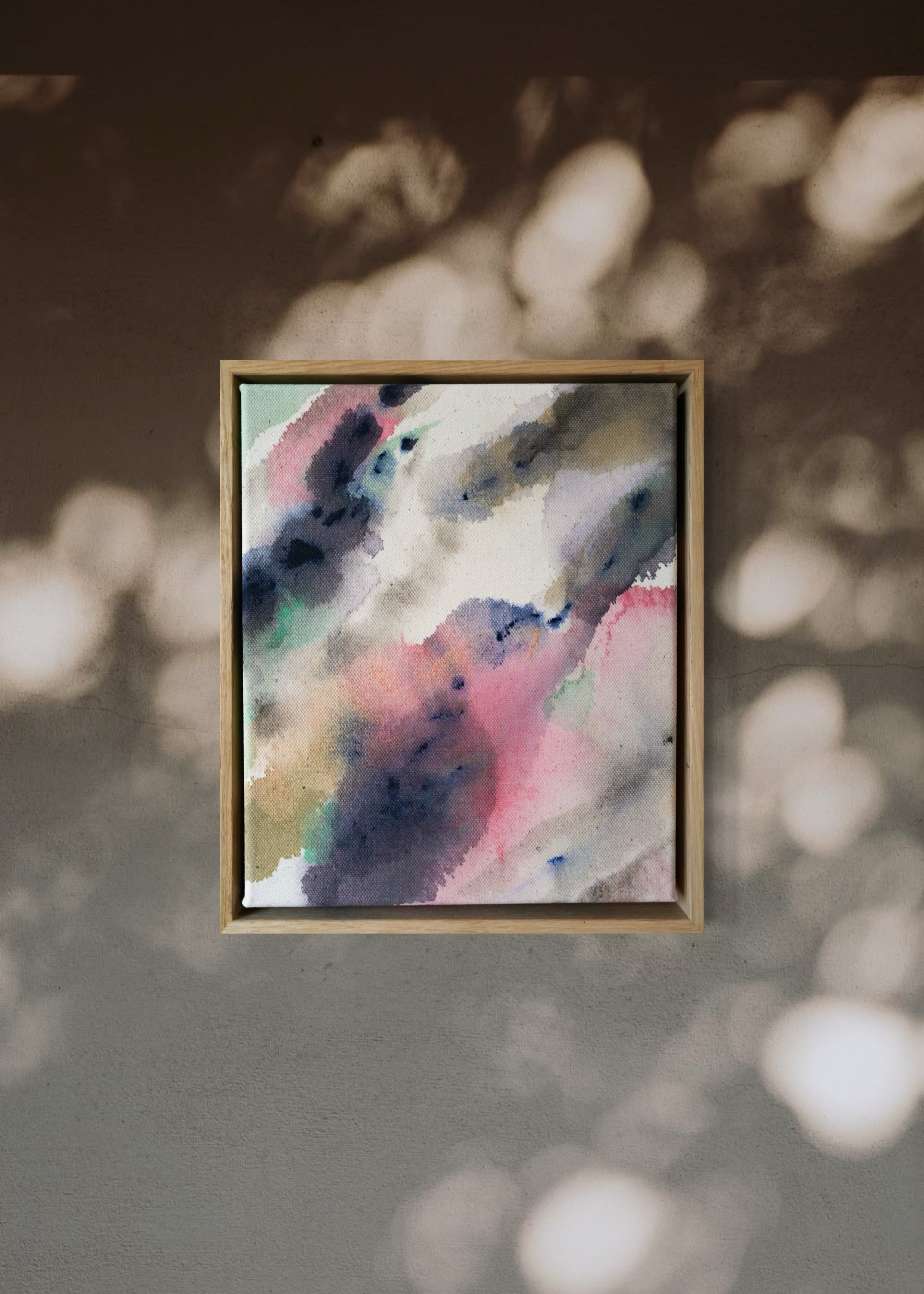 Abstract acrylic painting in a wooden frame displays blended swirls of pink, blue, and earthy tones on textured cotton canvas, evoking a serene mood.