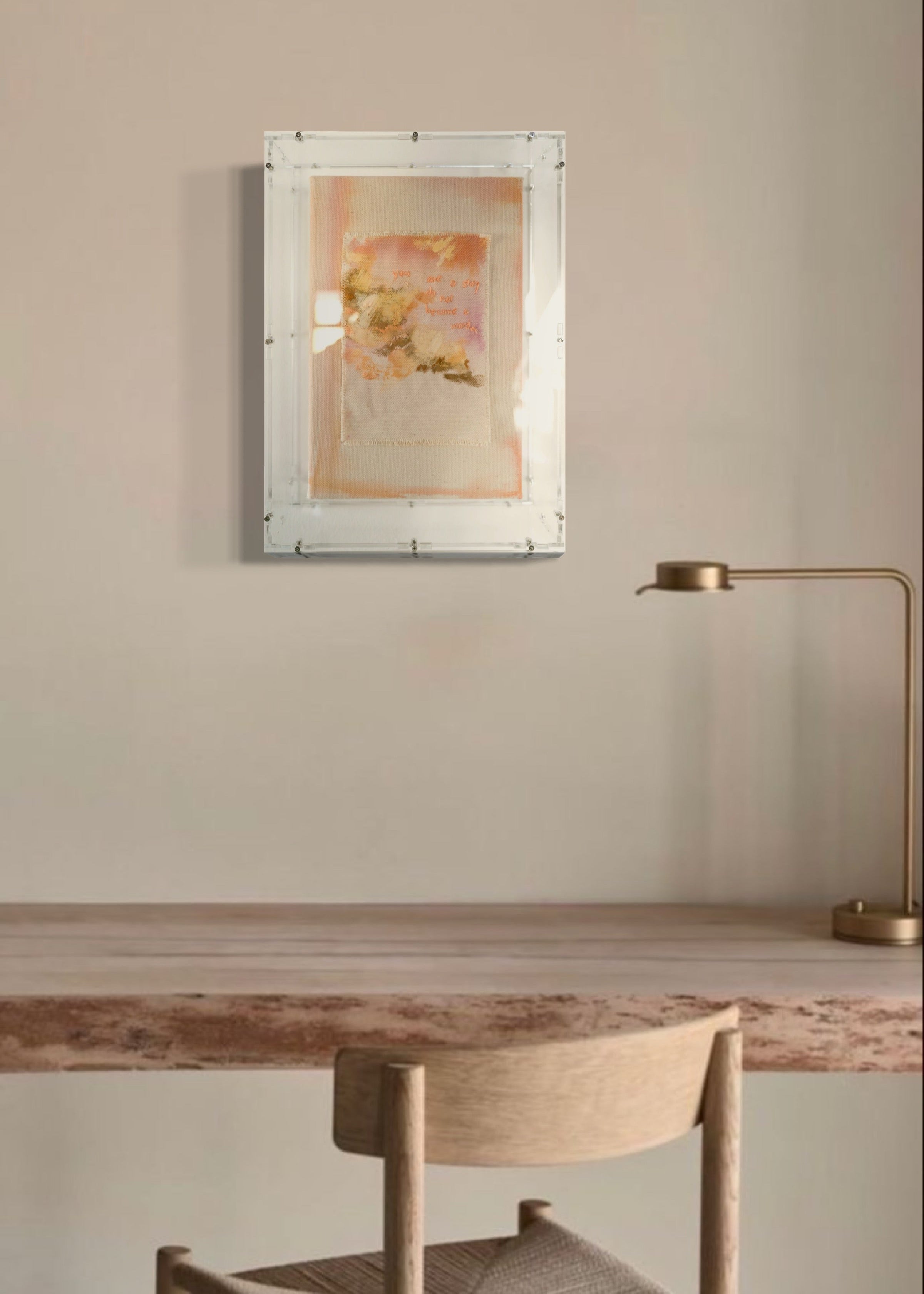 This textured abstract artwork showcases soft pastel shades of pink and orange. It features gentle brushstrokes and embroidered text that reads, "You are a story; do not become a word." The piece is elegantly framed in clear acrylic.