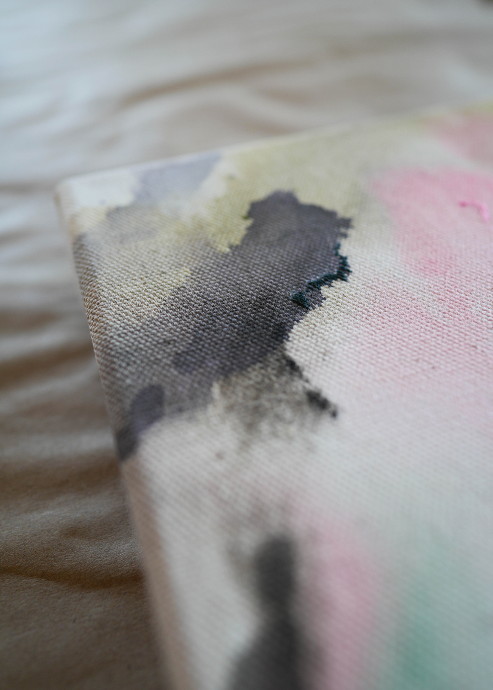 Abstract acrylic, fluid painting with soft pink, peach, green, and dark grey splashes, framed by light wood, conveying an impressionistic and soothing tone.
