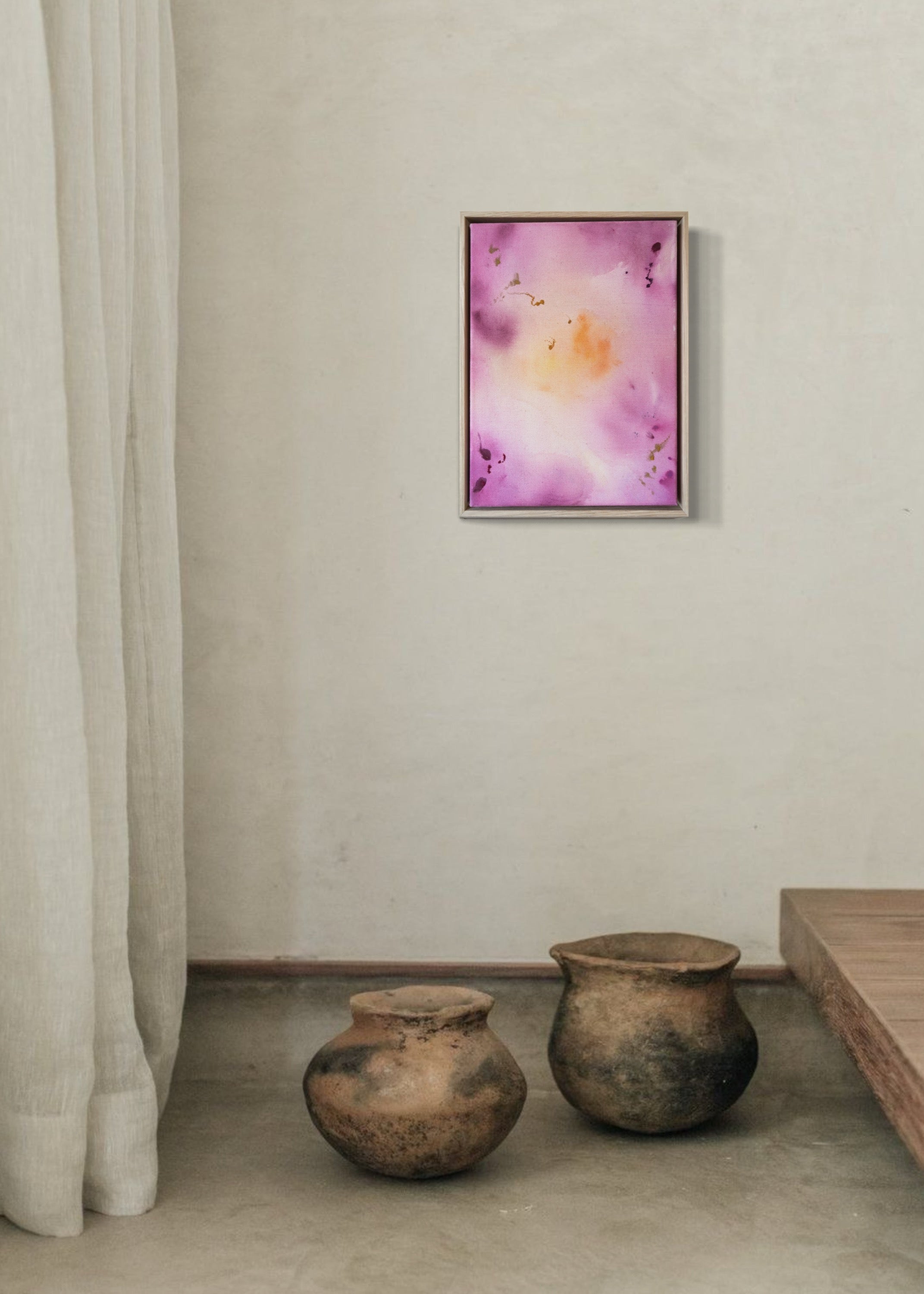 Abstract painting featuring soft pink, purple, and orange hues blending together with embroidery details of gold and dark purple on a canvas, framed in light wood.