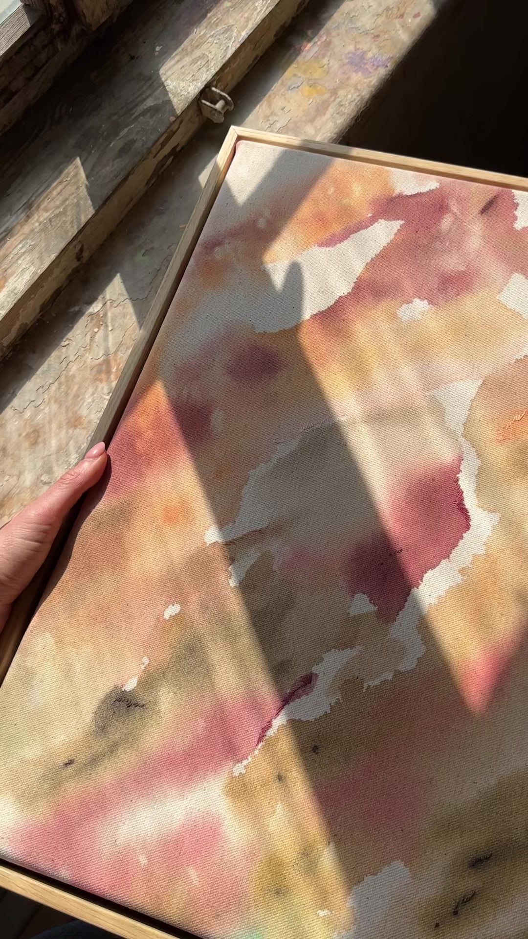 Abstract painting featuring soft, flowing shapes in shades of pink, beige, orange, and green shades, with a textured appearance  framed in oak wood.