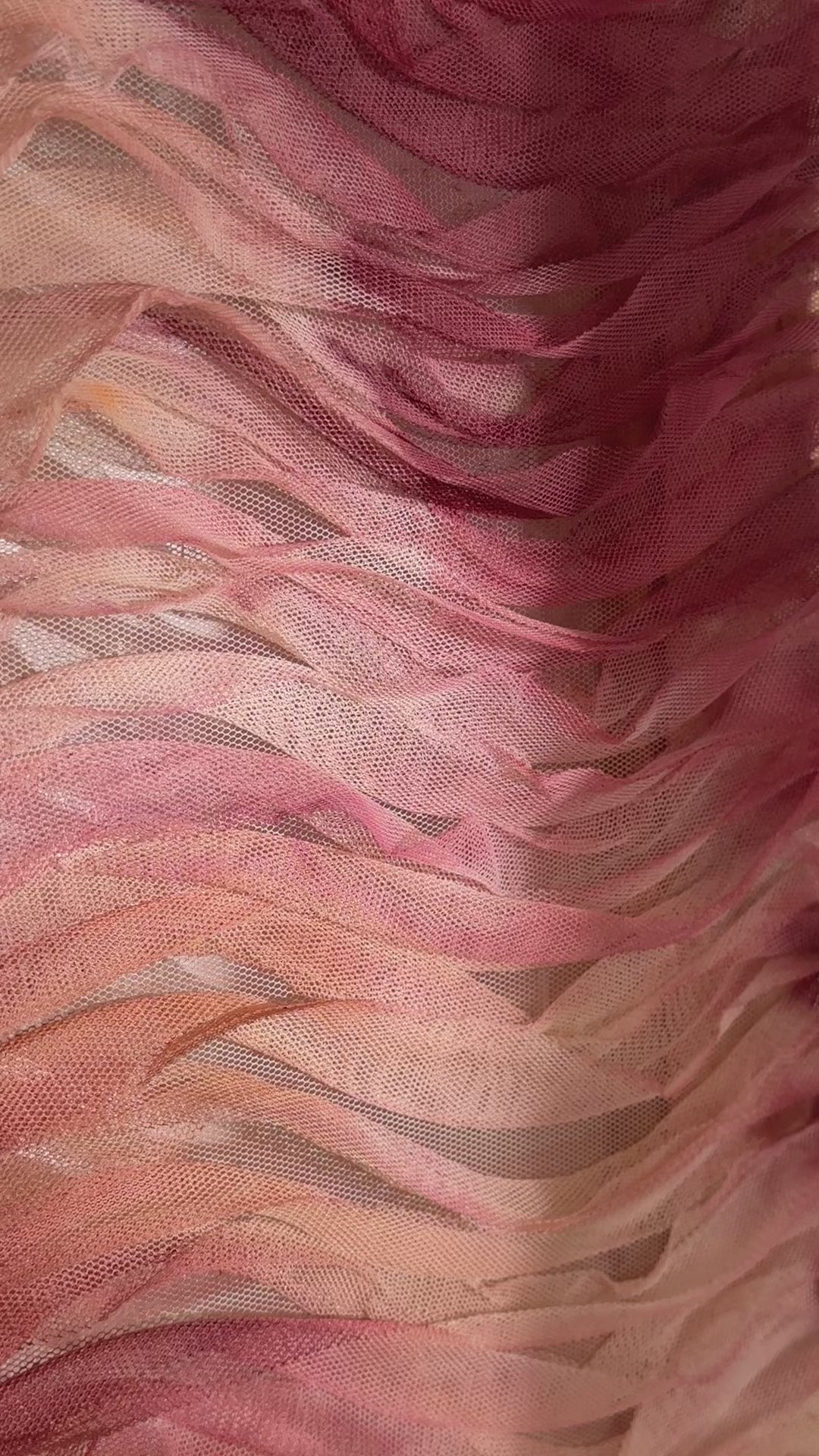 Abstract artwork featuring layered haute couture fabric from Carolina Herrera. Colors include light pink, red, orange, and deep red, arranged in wavy patterns.