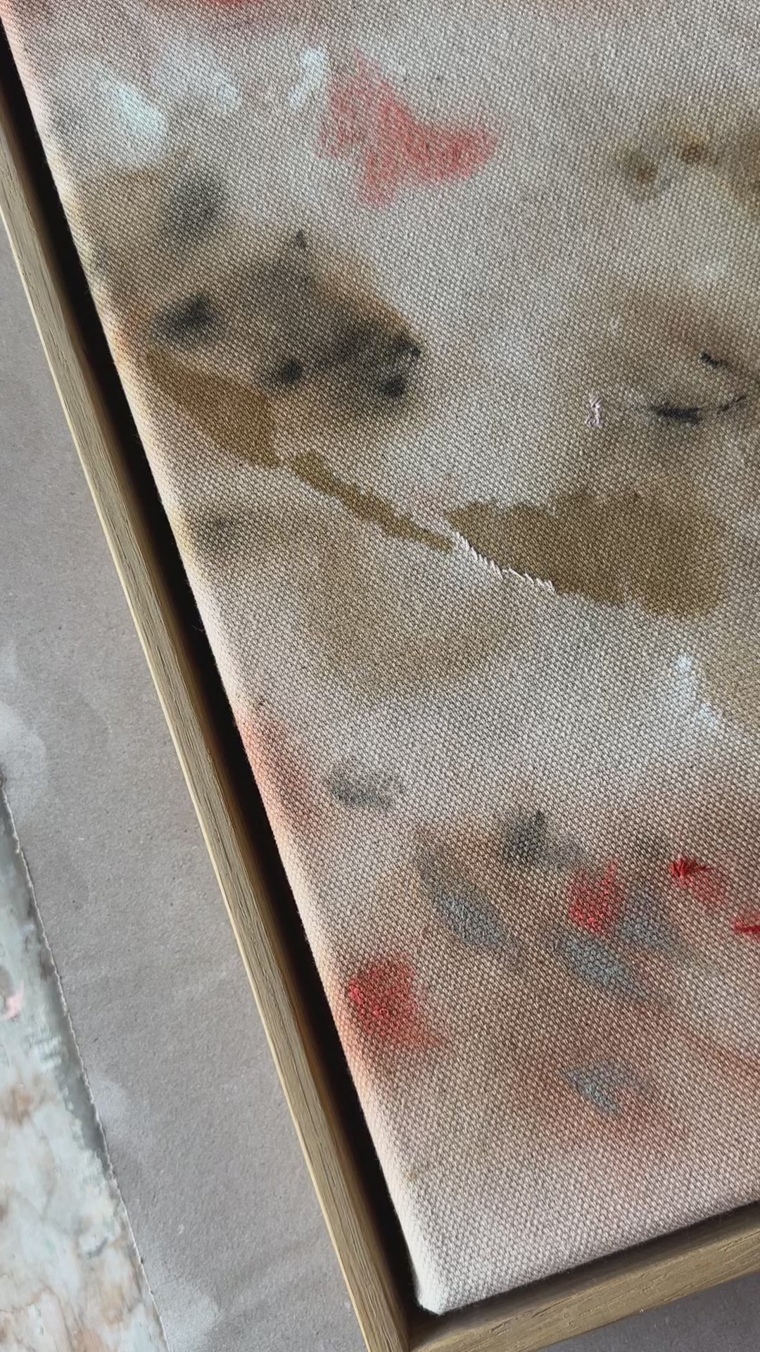 Abstract painting featuring soft, blended shapes in beige, brown, and hints of orange. The artwork has a textured, stitched surface and is framed in a light oak wood frame.